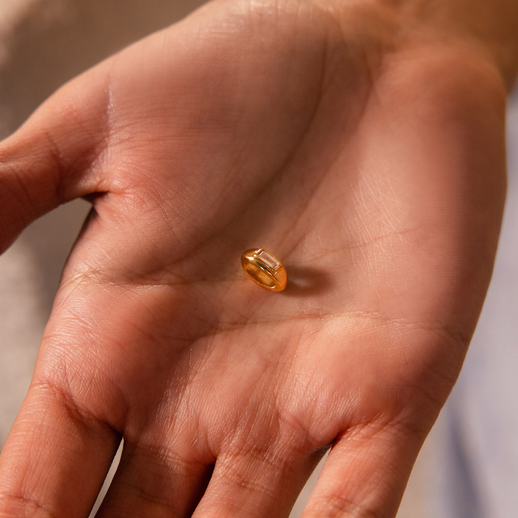 A close-up of a hand holding the Baguette Diamond Charm in the center of the palm.