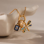 The Abalone Dragonfly Charm, a gold necklace featuring iridescent wing details, is displayed on a white sculpted ceramic hand.