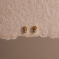 Tiny Duo Topaz Flatback Studs with a delicate diamond accent, displayed on a textured beige paper background.