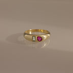 The Toi et Moi Dome Ring features a rectangular clear stone and a round red stone set side by side, creating a bold birthstone-inspired look.