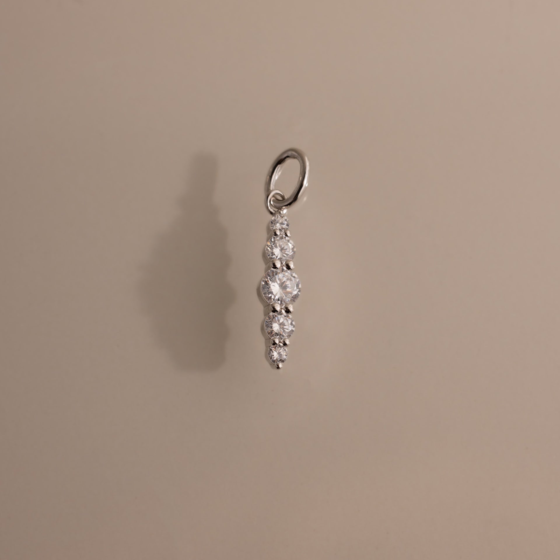 The Ombre Lace Diamond Charm features five round diamonds in a vertical row, ideal as a birth month gift or personalized pendant, shown on a beige background.