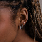 Close-up of an ear with various silver earrings against a blurred background