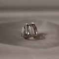 Pair of silver hoop earrings on a beige background