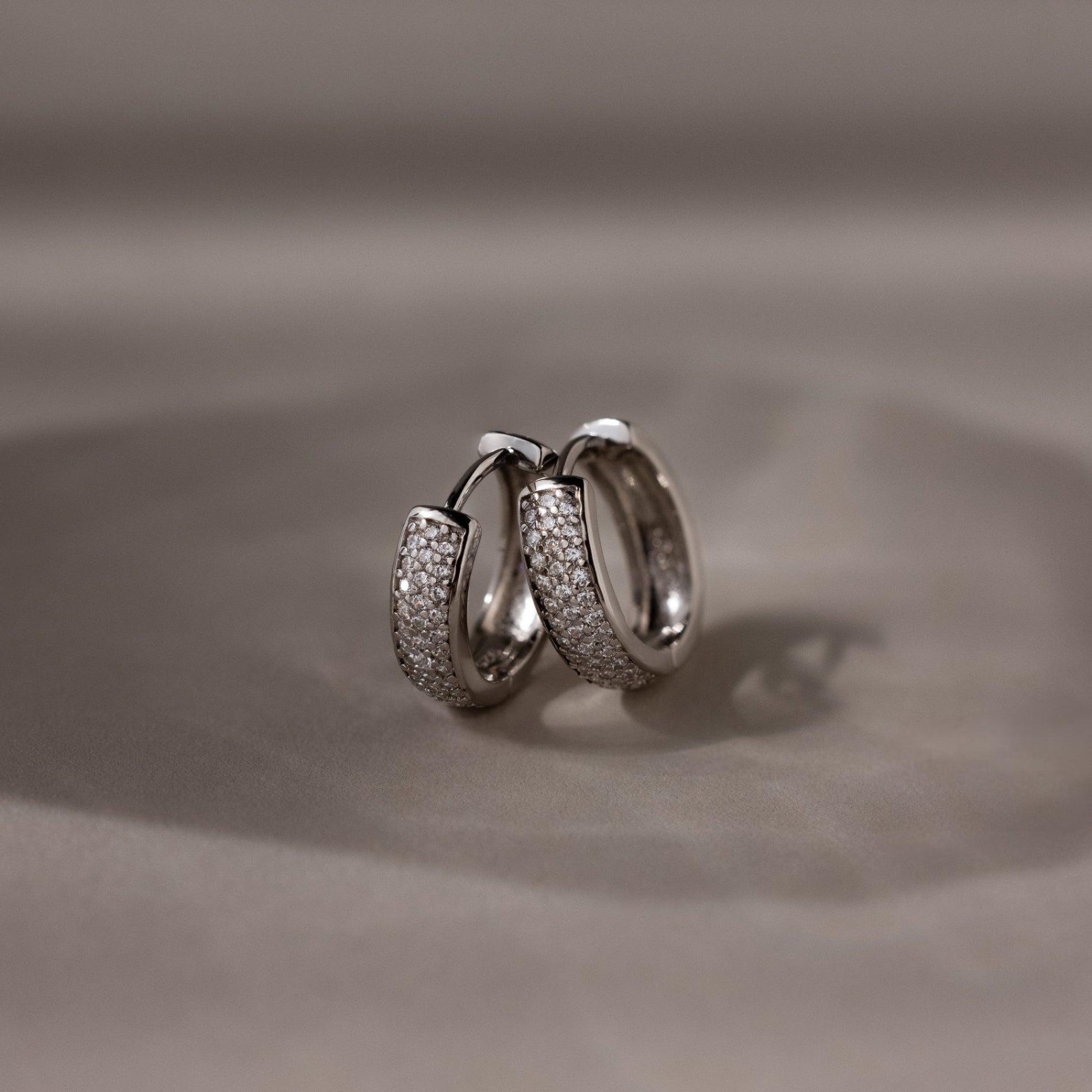 Pair of silver hoop earrings on a beige background
