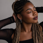 Woman with braided hair wearing silver earrings against a neutral background