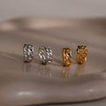 Four chain-link earrings in silver and gold on a reflective surface.