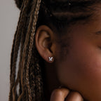 Close-up of a model with a diamond butterfly-shaped earring against a neutral background