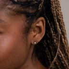 Model wearing small lightning bolt stud earrings in silver, styled as minimalist everyday jewelry on the ear.