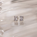 Silver stud earrings with clear rectangular gemstones on a white glass background