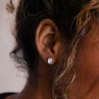 Close-up of a model wearing a silver diamond earring with blurred background