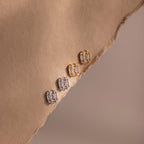 Pair of gold and silver diamond earrings on a beige fabric surface