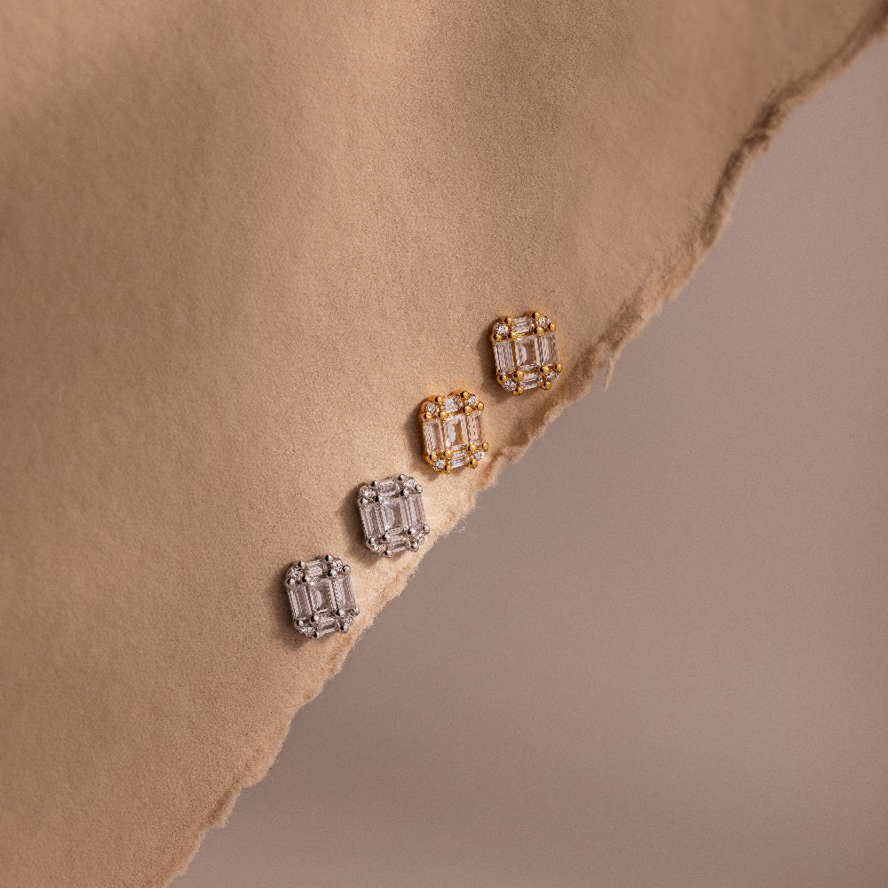 Pair of gold and silver diamond earrings on a beige fabric surface