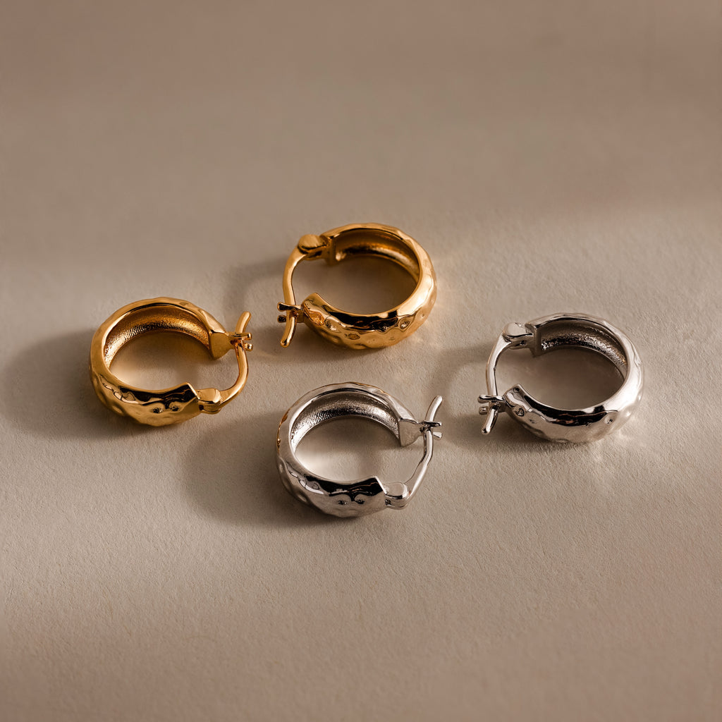 Bold Hammered Huggies in gold and silver with a textured finish are shown on a neutral background—ideal minimalist earrings for a modern look.