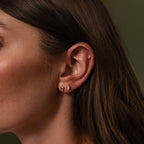 Close-up of a womans ear with Diamond Bezel Flatback Studs Set in 18K Gold, her brown hair tucked behind her ear.