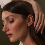 A woman with long brown hair showcases the Diamond Bezel Flatback Studs Set in Silver on her ear, with her hand resting on her head.