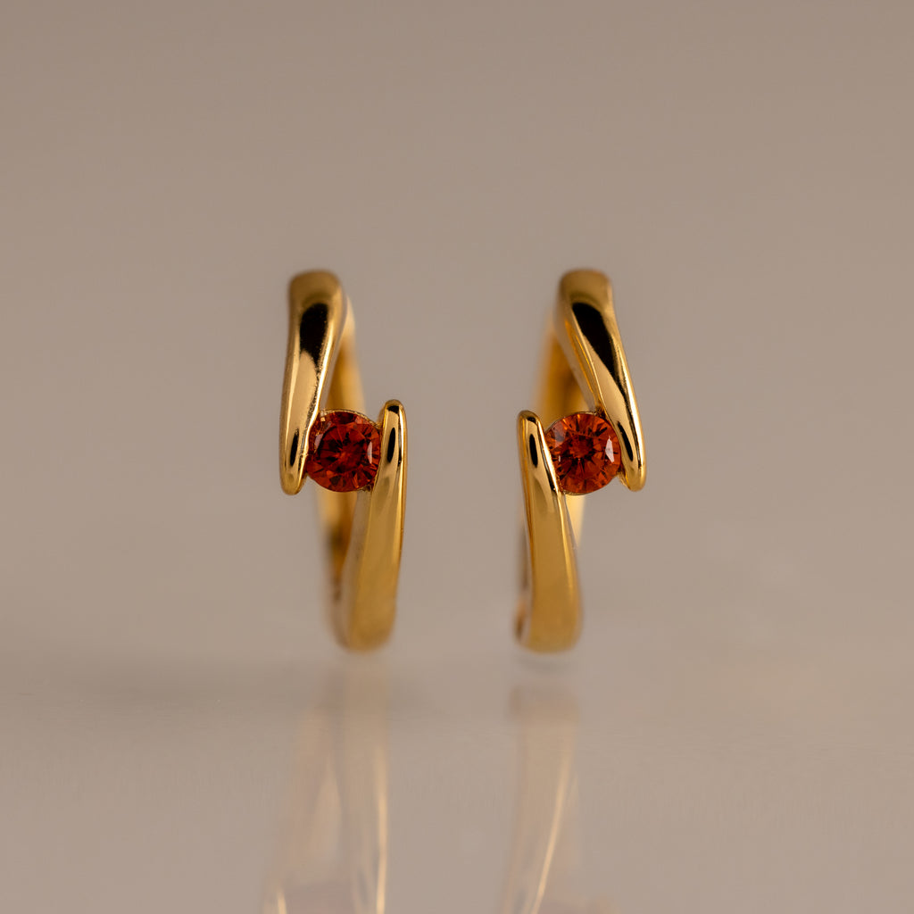 Floating Garnet Huggies: Twisted gold hoop earrings with a wavy design, each featuring a round garnet center—perfect personalized jewelry for birthstone lovers.