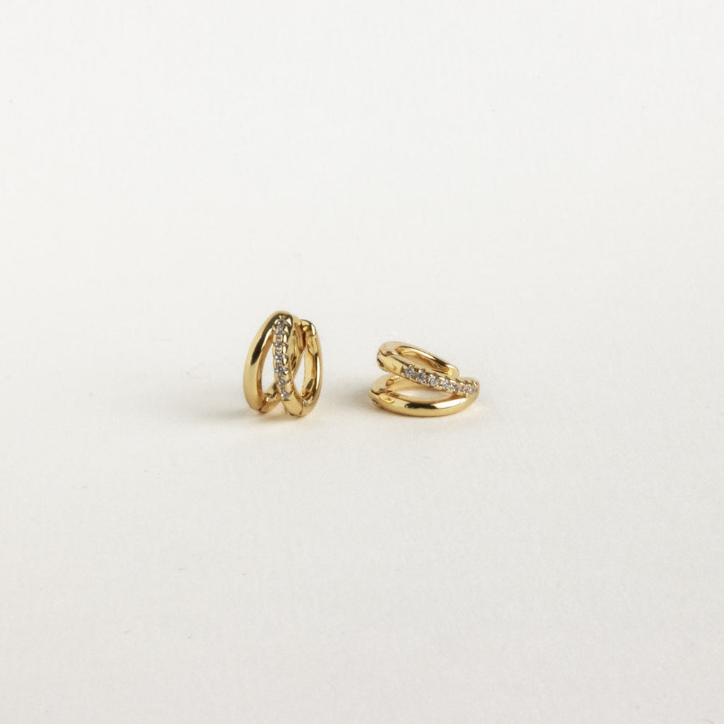 Two small gold Amelia Duo Huggies featuring embedded clear stones and pave accents, shown on a plain white background.