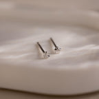 Silver moon and star-shaped earrings on a textured beige jewelry dish