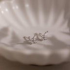 Silver butterfly-shaped diamond earrings on a soft white background