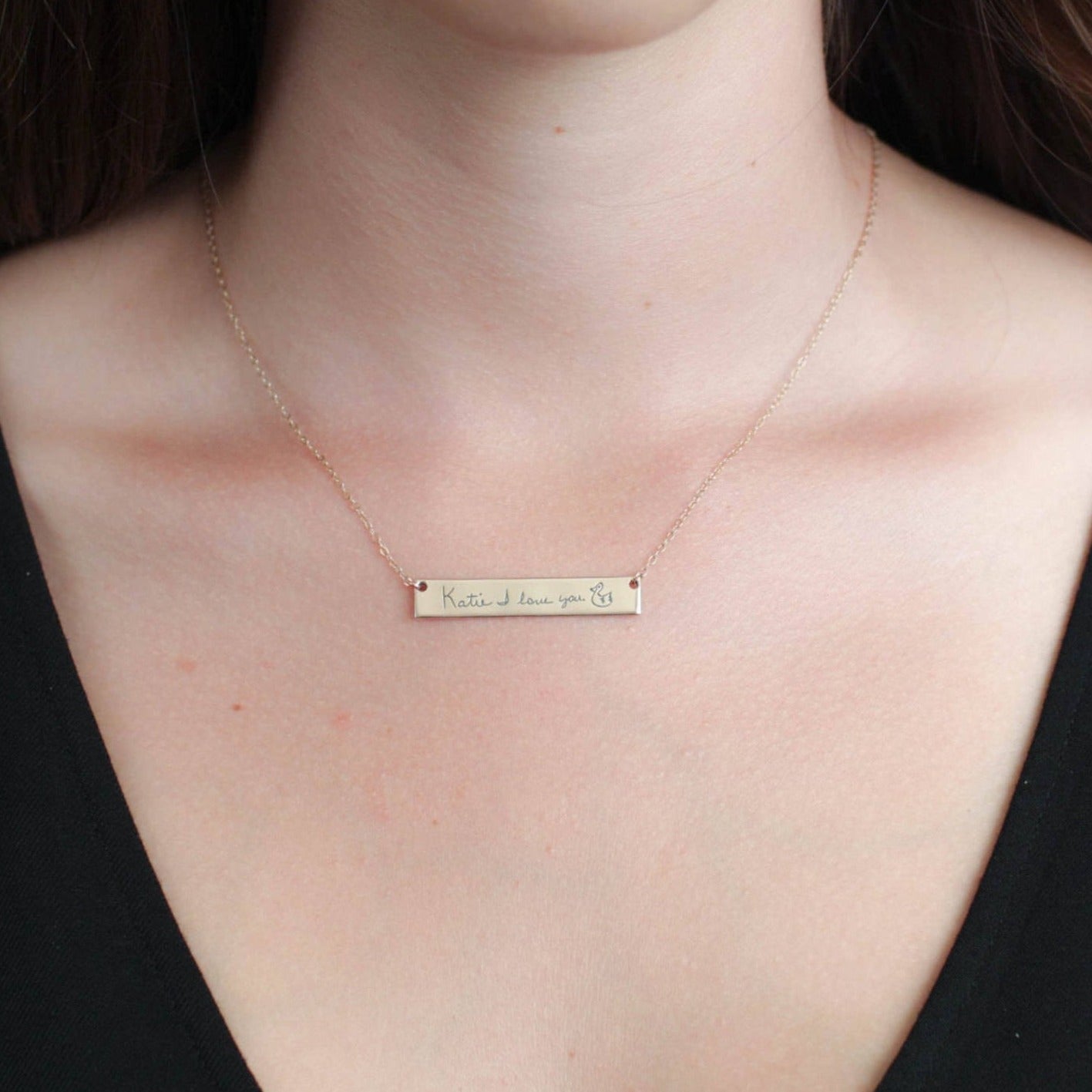 Necklace with a bar pendant on a person's neck against a black background
