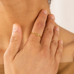 A hand wearing the Knot Ring in Sterling Silver rests on a person’s neck, forming a symbolic gesture against a neutral background.