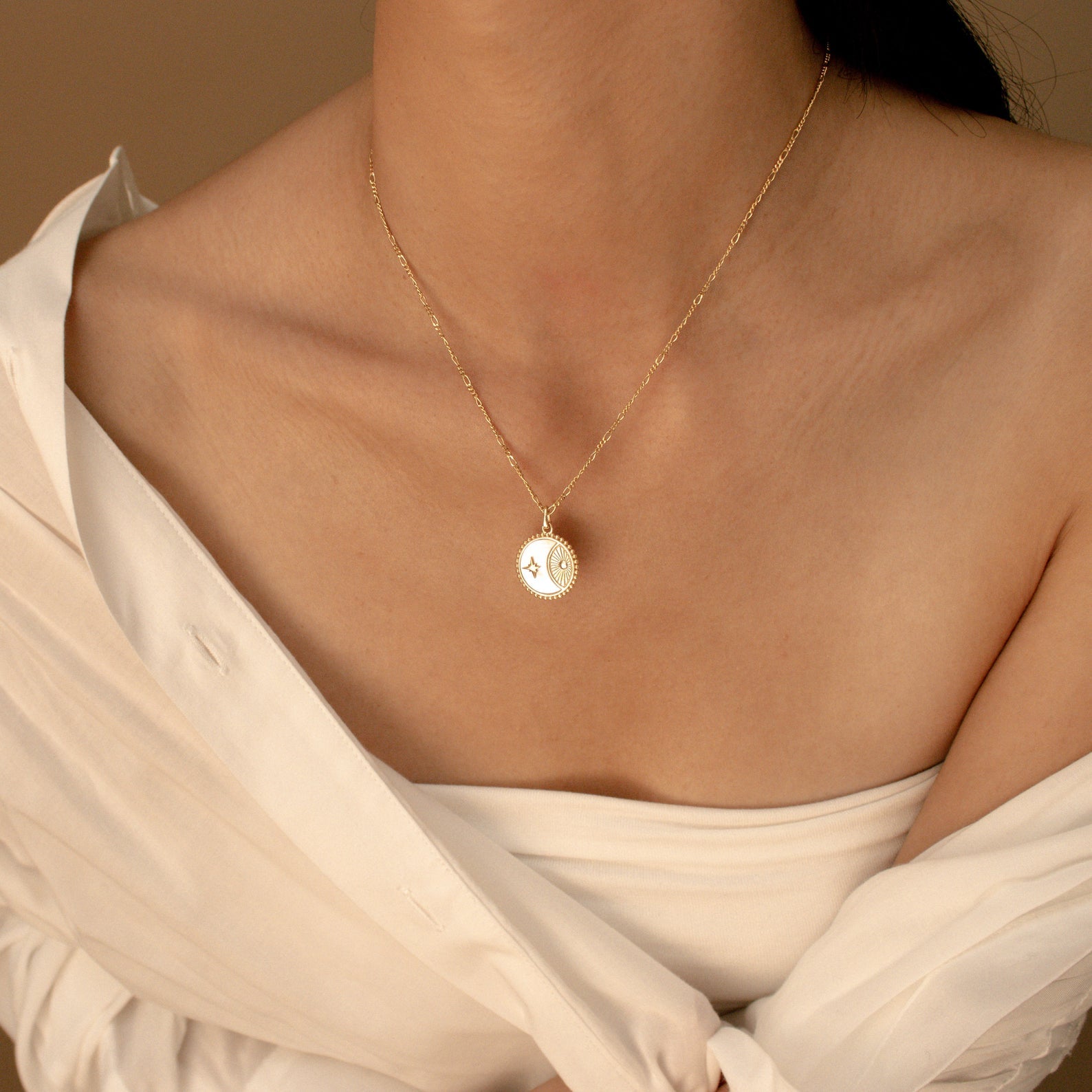 A woman in an off-shoulder white top wears the Gabi Coin Necklace with a round pendant.