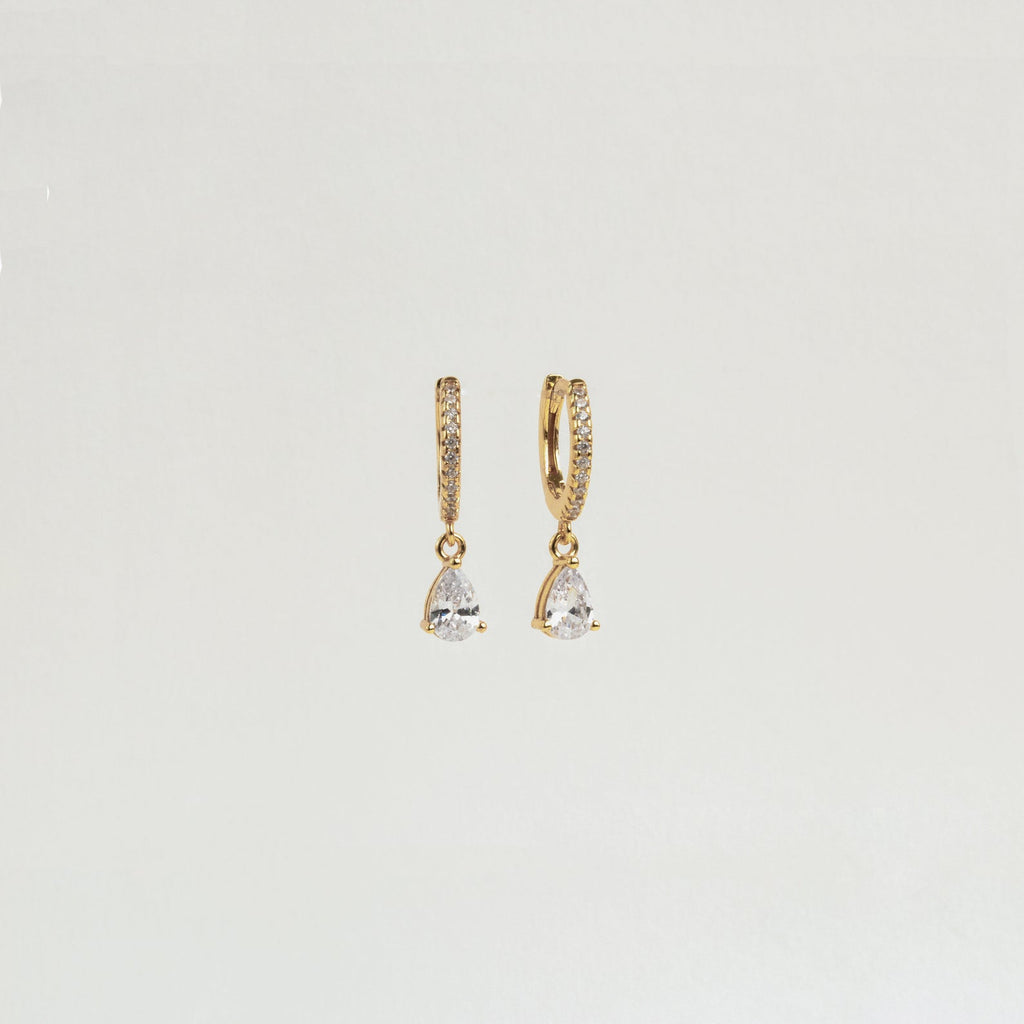 Diamond Drop Huggies in 18K Gold—gold hoops adorned with diamonds and clear teardrop pendants, ideal for adding subtle elegance to semi-formal looks. Displayed on a plain white background.