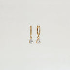 Diamond Drop Huggies in 18K Gold—gold hoops adorned with diamonds and clear teardrop pendants, ideal for adding subtle elegance to semi-formal looks. Displayed on a plain white background.