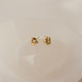 Love Knot Studs in Sterling Silver are shown on a smooth, light-colored stone background—these symbolic earrings make a perfect unity gift.