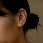 Close-up of a woman's ear wearing Love Knot Studs in Sterling Silver, with dark hair in a low bun—symbolic jewelry perfect as a unity gift.