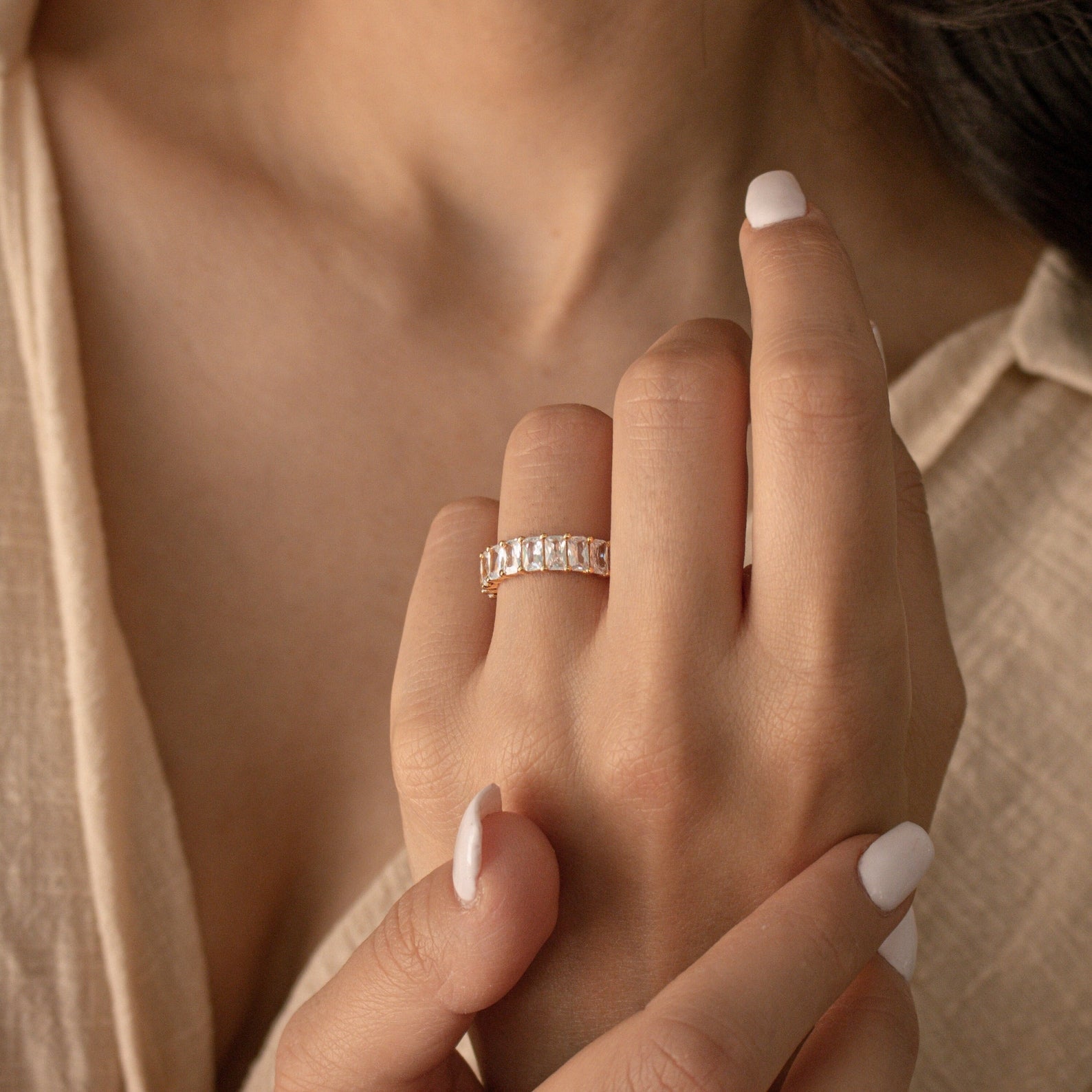 A hand with white nail polish wears the Colette Eternity Ring in Silver on the ring finger.