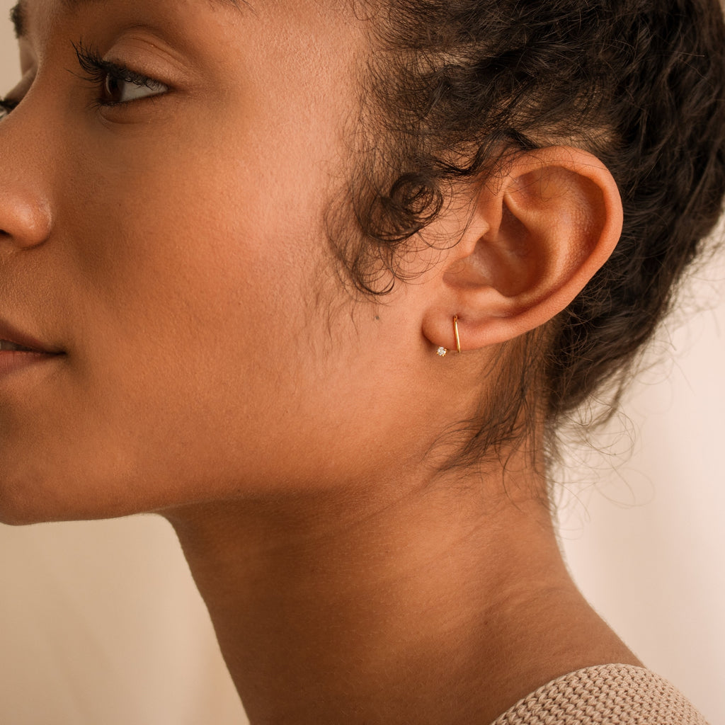 Jady Wire Diamond Hoop earring in 18K gold on ear, slender open hoop with pavé diamonds.