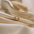 The Giana Marquise Huggies are shown on soft beige satin with dried grass, creating a subtle look that's perfect for everyday elegance.