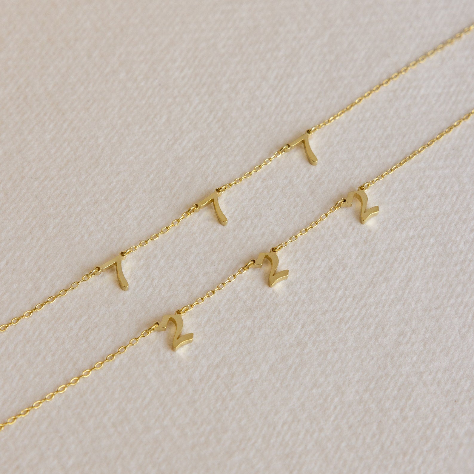 The Alice Spaced Number Necklace set features three delicate gold chains with small gold number pendants—one necklace with a "1" and two with a "2"—perfect for anyone who loves a minimalist, elegant look.