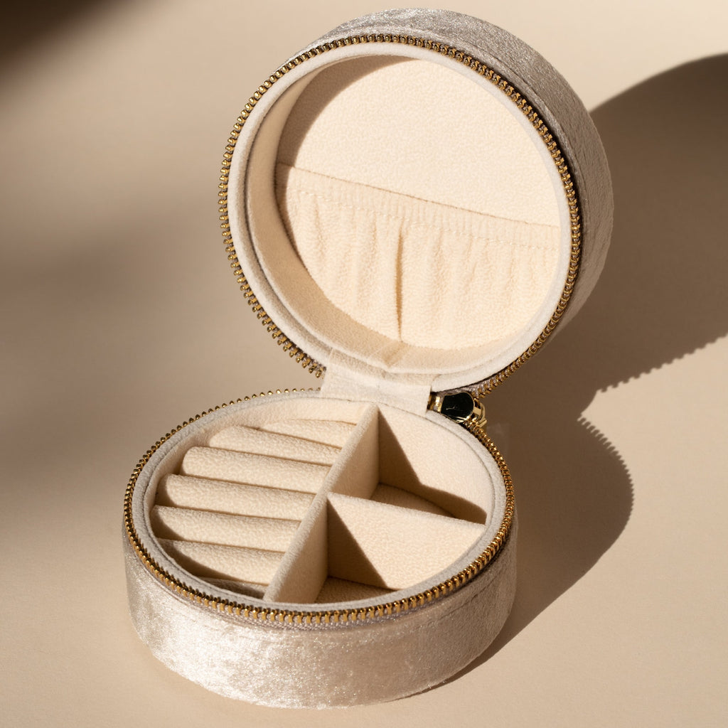The Round Velvet Jewelry Case features beige velvet, a zipper closure, and compartments for rings and accessories—making it the ideal travel organizer for minimalists.