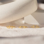 Three Nella Duo Initial Rings with AS, CK, and RL are displayed on a soft beige surface with a white prop—personalized jewelry that's perfect as an anniversary gift.