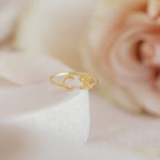 The Dainty Duo Initial Ring with C and K, framed by soft pink and cream flowers, makes a perfect personalized gift for anniversaries.