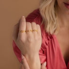 A woman in a pink top displays three gold Dainty Duo Initial Rings with script letters on her fingers, making them a perfect anniversary gift.