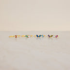 Five Cluster Baguette Birthstone Rings with colorful gemstones are arranged in a row on a light marble surface against a beige background, perfect as birthstone or personalized statement rings.