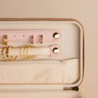 The Rectangle Velvet Jewelry Case displays gold and purple rings and earrings elegantly arranged on pink velvet and beige holders.