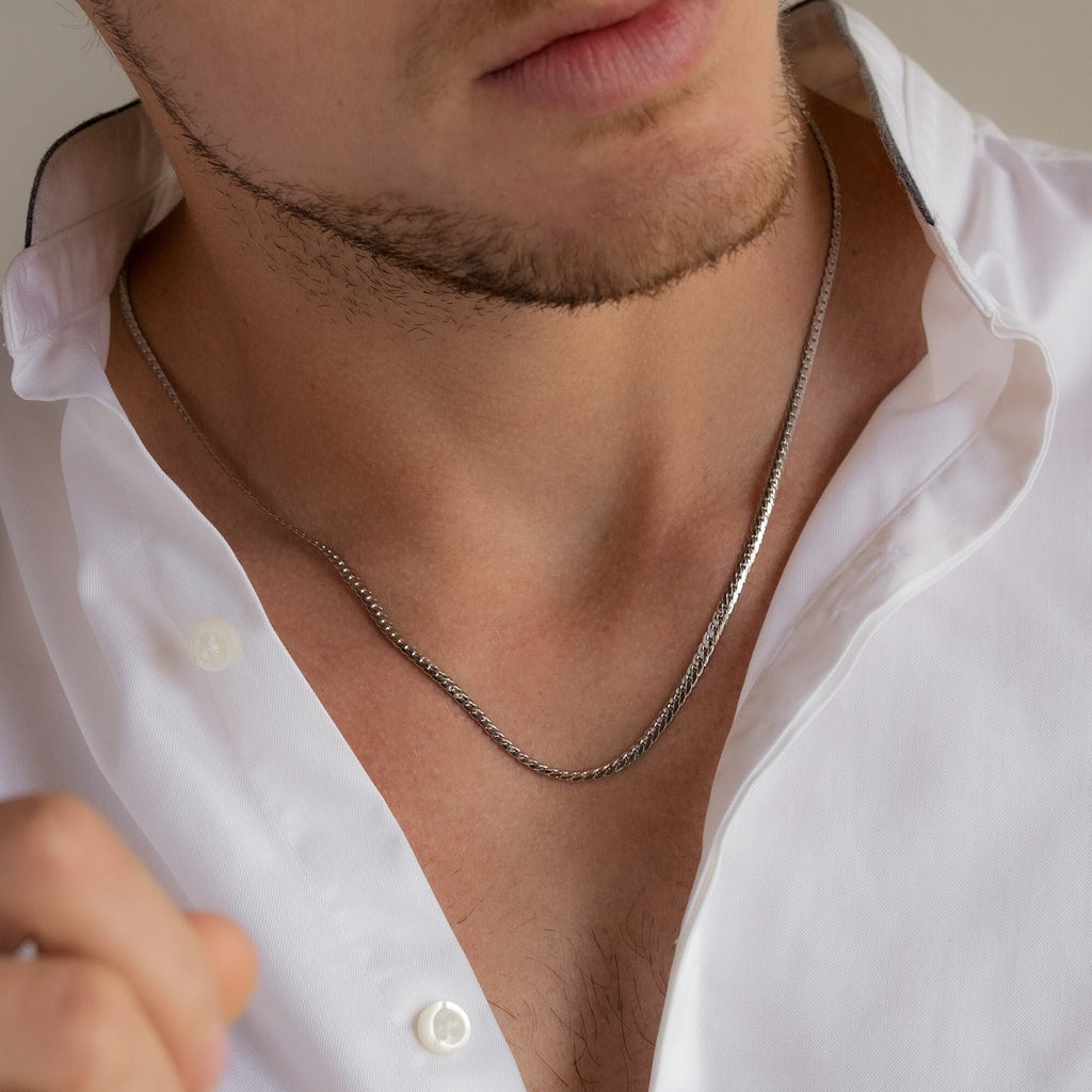 A man in a white open-collar shirt wears the Men's Snake Chain Necklace—a sleek, minimalist piece that adds a modern touch to men's jewelry.