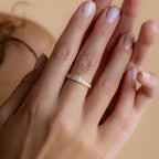 A hand wearing the Art Deco Diamond Ring from the 18K Gold Earrings & Ring Set, with baguette-cut stones in a vintage-inspired design, gently touches another hand.