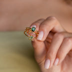 Three gemstone rings, including the Agate Emerald Ring, held between fingers to show their different colors and clarity.
