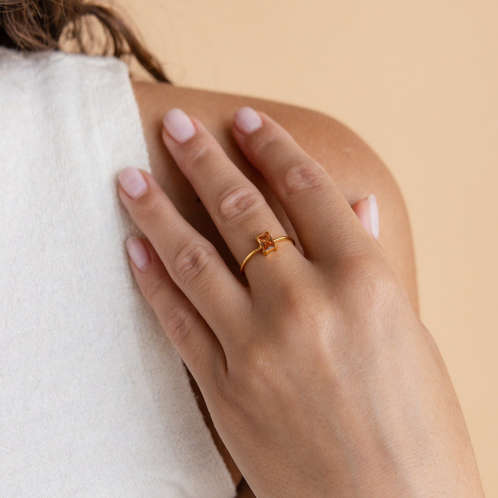 A hand with light pink nails wearing the Citrine Emerald Ring rests on a shoulder—the ideal accent for anyone who loves the warm glow of November’s birthstone.