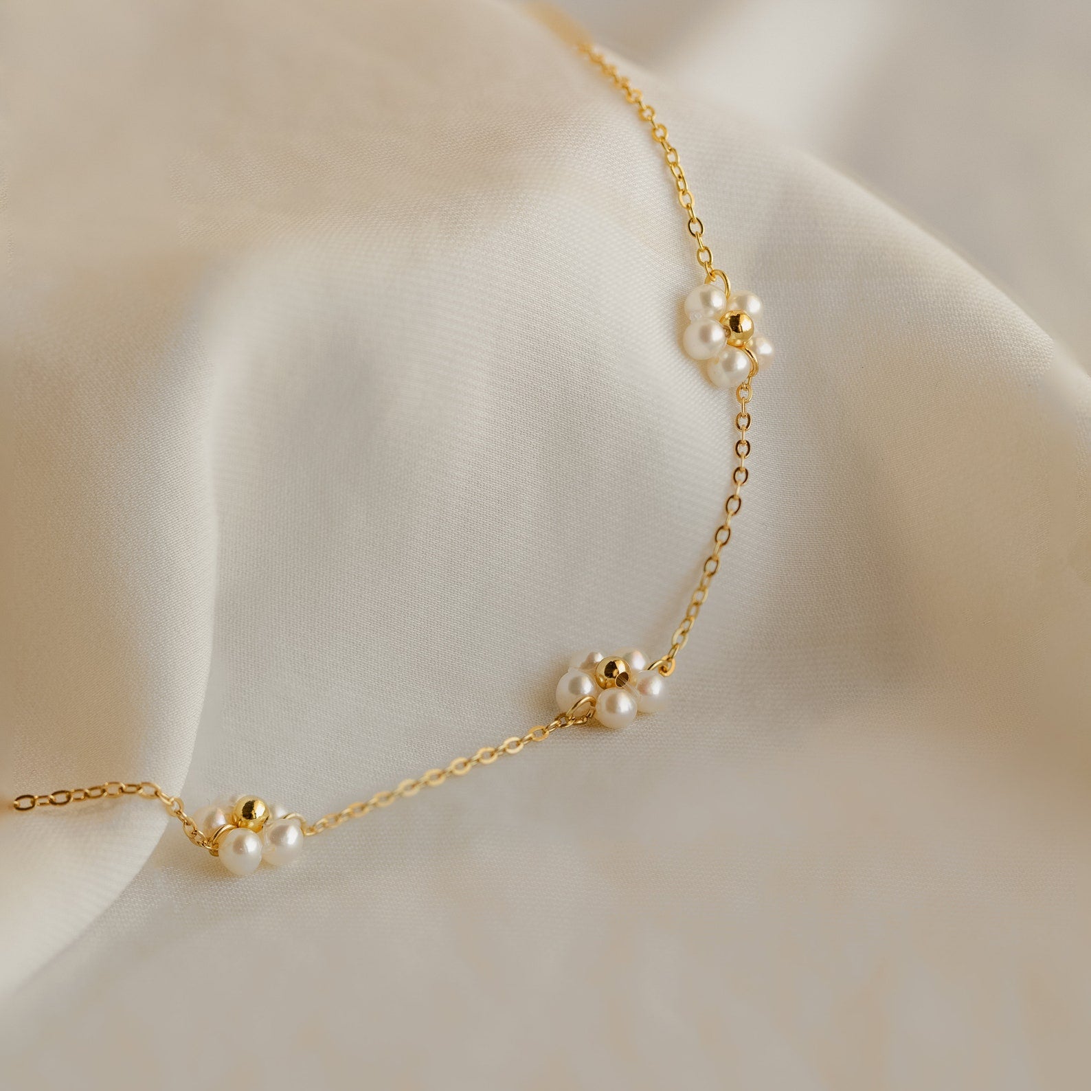 The Flower Pearl Station Necklace is elegantly displayed on soft, light fabric—an ideal Mother’s Day present or a thoughtful bridesmaid gift.