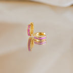 Magenta Opal Inlay Huggies are showcased on a reflective surface with a soft background.