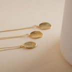 Three Custom Fingerprint Necklaces in Rose Gold with round engraved fingerprint pendants rest on a beige surface—each piece is a unique and sentimental gift.