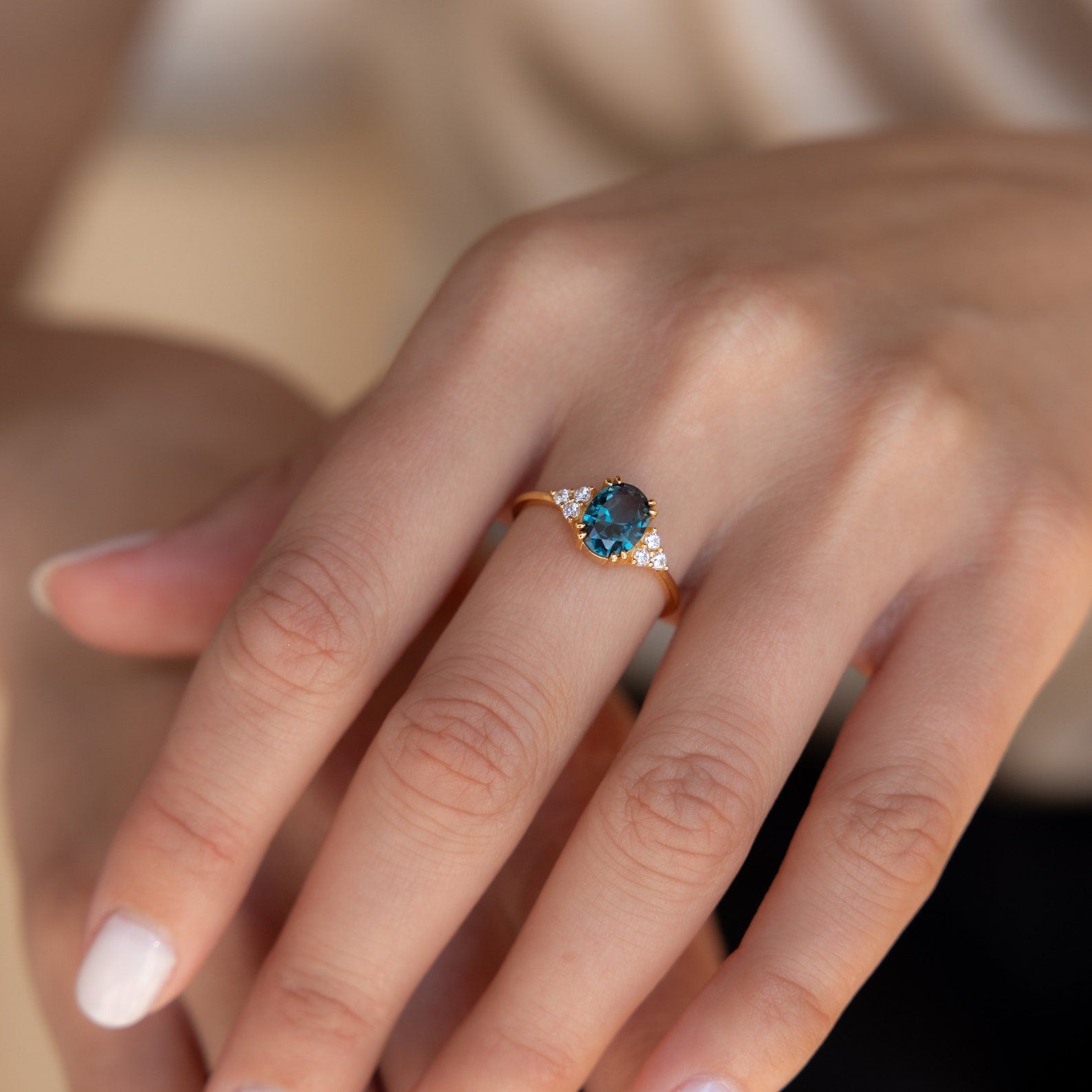 Close-up of the ring on hand, highlighting the vibrant blue stone flanked by clusters of diamonds.