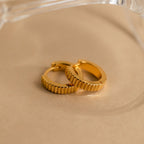 Ribbed Huggies displayed on a beige surface with a clear object in the background, offering the perfect balance of bold style and dainty elegance.