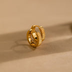 Ribbed Huggies feature a textured, ridged design and rest on a beige surface—ideal for adding bold elegance to any look.